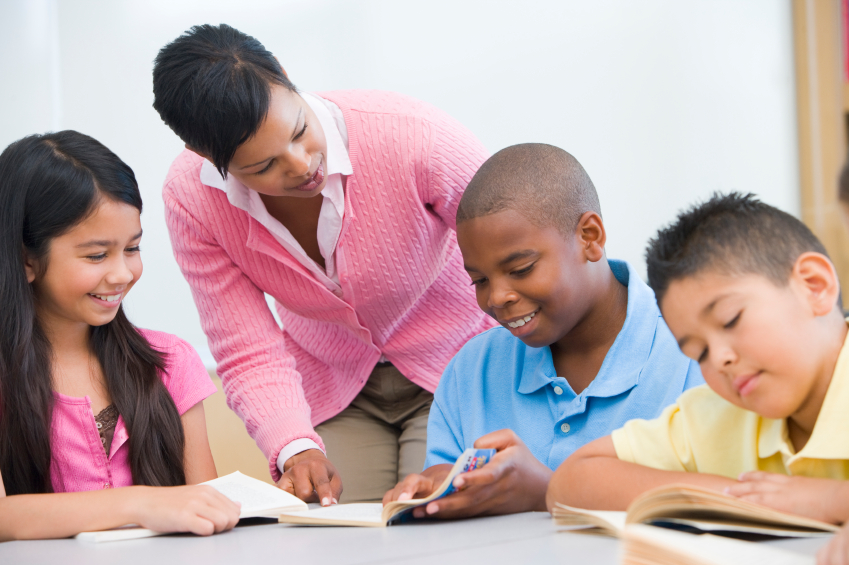 Picture of female instructor pointing out a section on a page to children