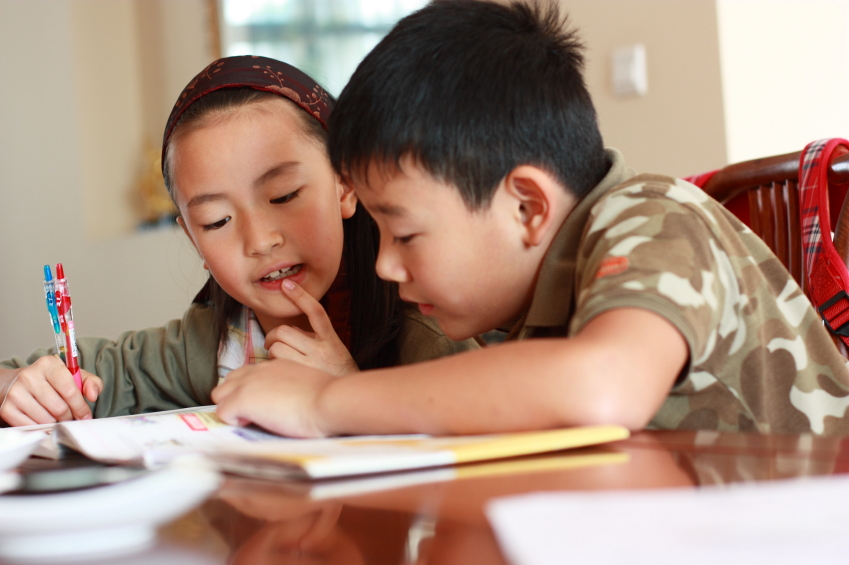 Photo of two children, boy and a girl studying