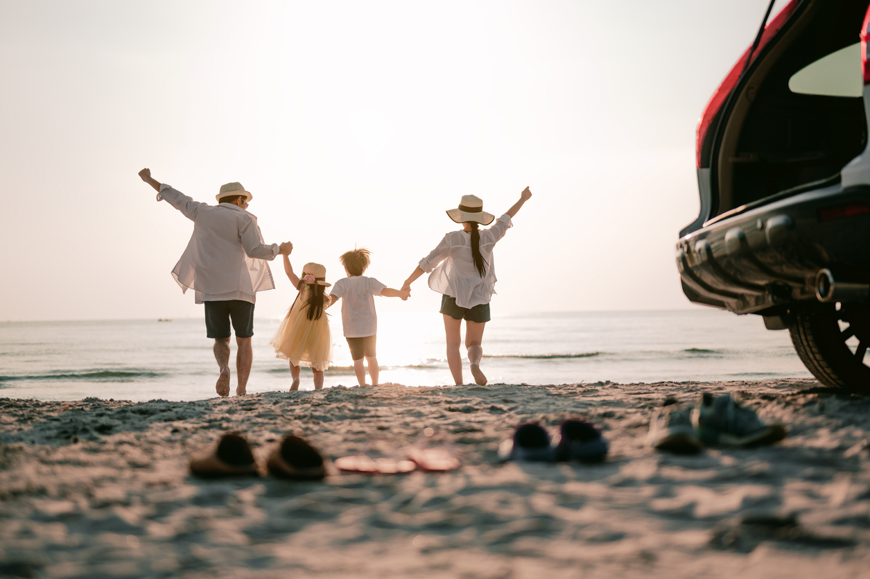 Photo of a family of four running towards ocean on a beach