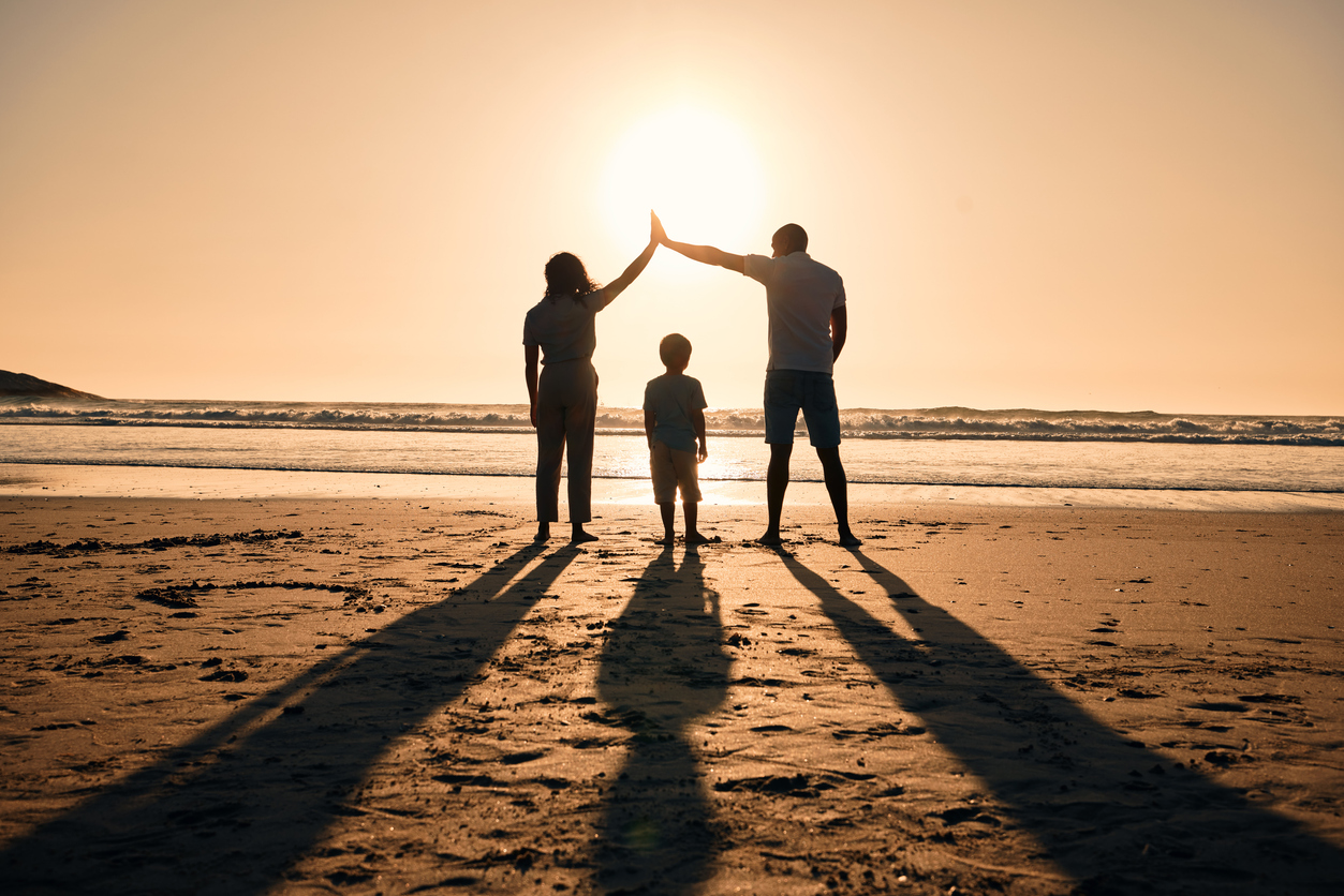 Family silhouette at the beach during sunrise, parents protect child while outdoor