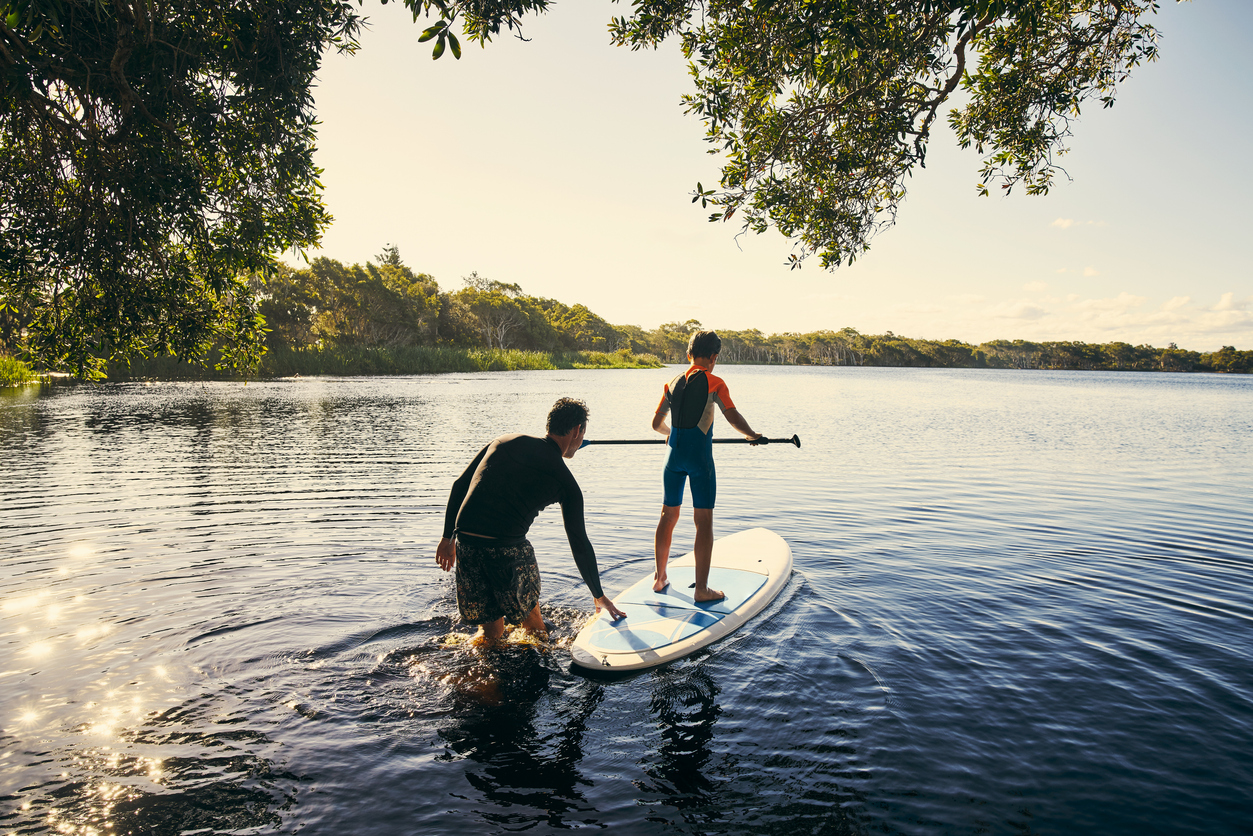 Photo of a father and son enjoying a day outdoors paddle boarding